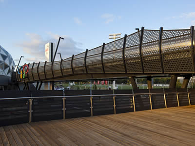 Perforated metal infill panels are installed on the side of a footbridge.