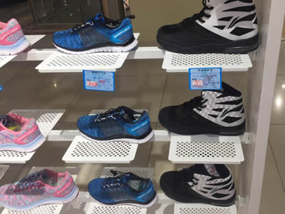 White perforated metal shoe display racks with square holes in staggered rows, and many shoes are put on them.