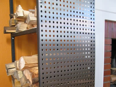 A perforated metal storage rack with round holes in straight rows and two layers, and many firewood is in it.
