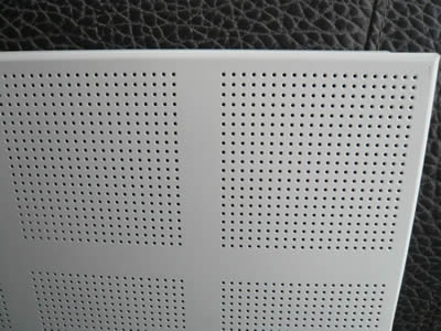A piece of perforated metal ceiling sheet with small round holes arranged to square in straight rows.