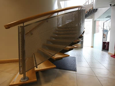 Perforated metal fences with round holes in staggered rows are on the side of staircase for protecting people.
